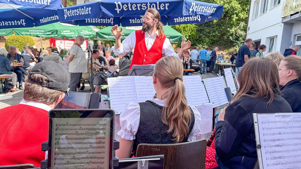 Dirigent Sebastian Schertel mit Publikum im Hintergrund